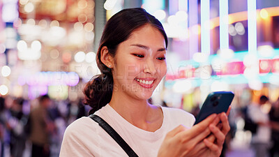 Buy stock photo Woman, phone and happy at night in city, reading and notification with chat, texting and contact in street. Person, smartphone and check on metro sidewalk, smile and app for social network in Japan