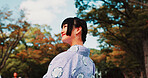 Green, park and girl in kimono with smile, thinking and outdoor sightseeing in nature with low angle. Culture, inspiration and Japanese woman in garden for traditional spring festival from behind