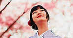 Cherry blossom, park and face of girl with kimono, thinking or outdoor sightseeing in nature with low angle. Culture, inspiration and Japanese woman in spring garden for traditional sakura festival