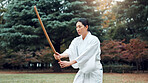 Culture, Japanese woman and outdoor for martial arts in training, exercise or sports as athlete. Person, weapon and heritage for challenge, combat and practice for self defense technique with bojutsu