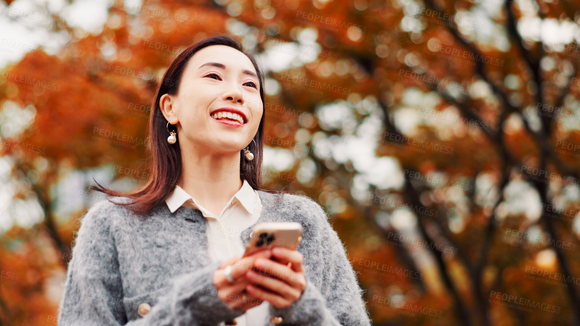 Buy stock photo Thinking, phone and happy woman outdoor for travel, text or message on app in Japan. Smile, mobile and Japanese person at park for dream, planning vacation or post on social media profile on internet