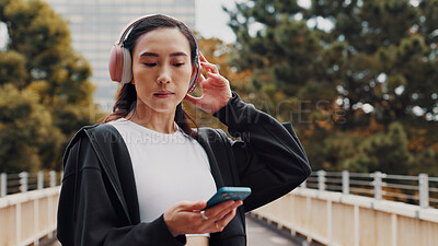 Buy stock photo Japanese woman, headphones and phone in city of listening to music, fitness podcast and social media. Female athlete, mobile and streaming radio of exercise routine, training website and Japan bridge