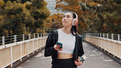 Buy stock photo Headphones, phone and running with Japanese woman in city for health, streaming and fitness podcast. Wellness, cardio and training with person listening to music in Japan for workout and marathon