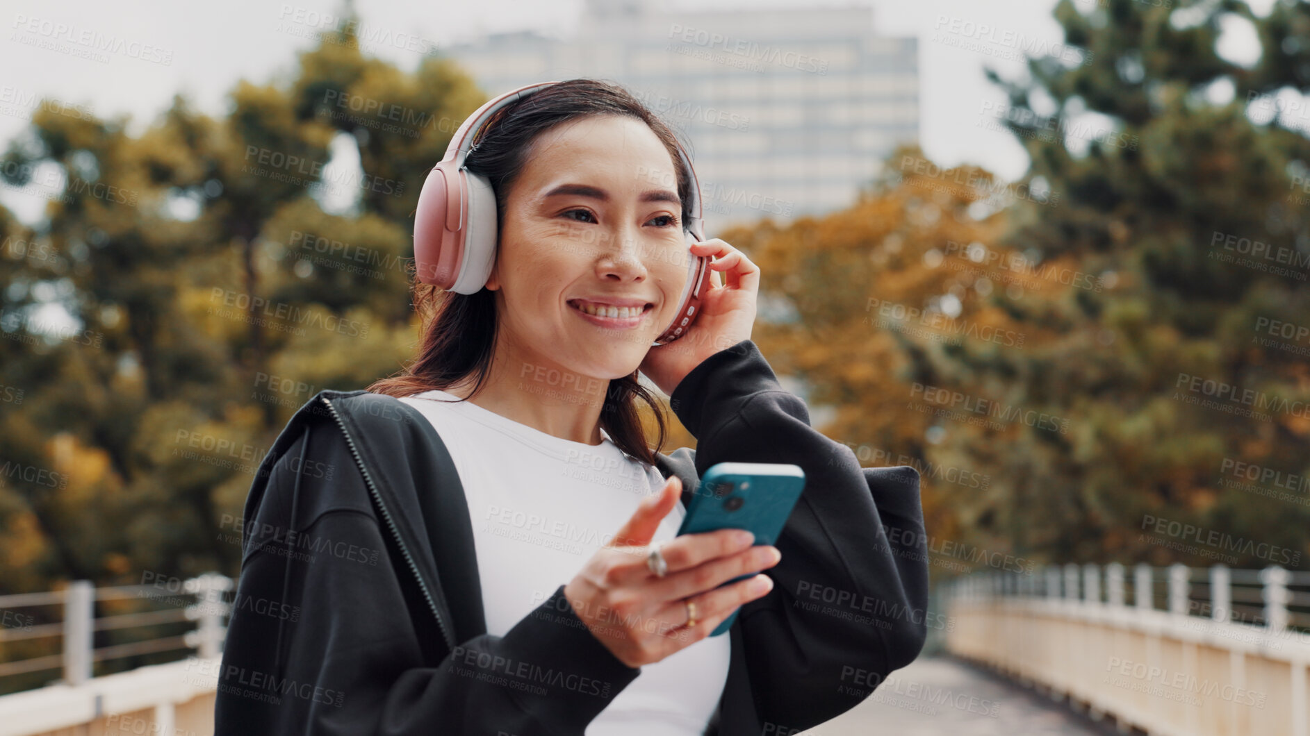 Buy stock photo Happy, woman and headphones with phone in city of listening to music, fitness podcast and social media. Athlete, mobile app and streaming radio for exercise routine, training website and Japan bridge