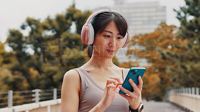 Buy stock photo Woman, headphones and typing with phone in city of listening to music, fitness podcast and social media. Athlete, mobile app and streaming radio of exercise routine, training website and Japan bridge