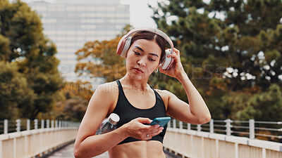 Buy stock photo Fitness, woman and headphones with phone in city of listening to music, cardio podcast and social media. Athlete, mobile app and streaming radio of exercise routine, training website and Japan bridge