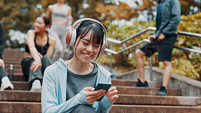 Buy stock photo Woman, fitness break and scroll with phone on park stairs with headphones for online exercise program. Sports, cellphone and Japanese athlete with website for workout, routine and outdoor in nature