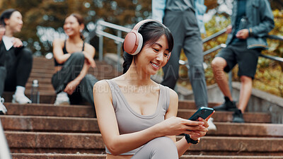 Buy stock photo Woman, fitness break and scroll with cellphone on park stairs with headphones for online exercise program. Sports, phone and Japanese athlete with website for workout, routine and outdoor in nature