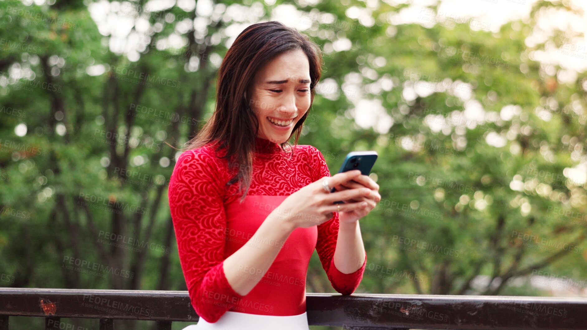 Buy stock photo Woman, phone and texting on bridge in park with laughing, excited and reading post on mobile app in summer. Person, smartphone and happy with contact, chat and notification with funny meme in Japan