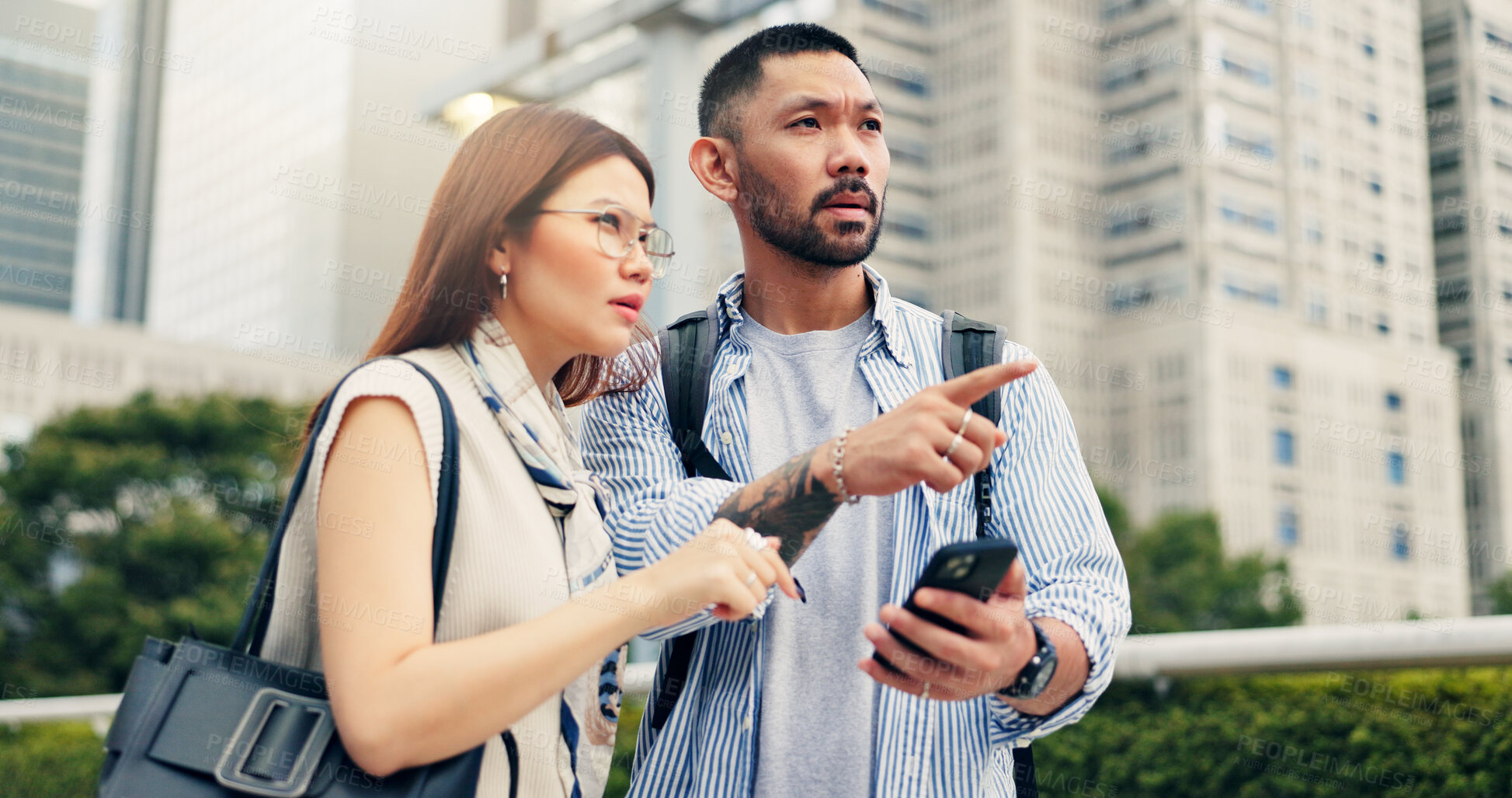 Buy stock photo Couple, phone and point for direction in city, travel and mobile app for location, landmark and help in street. People, man and woman with smartphone, talking and search on urban sidewalk in Japan