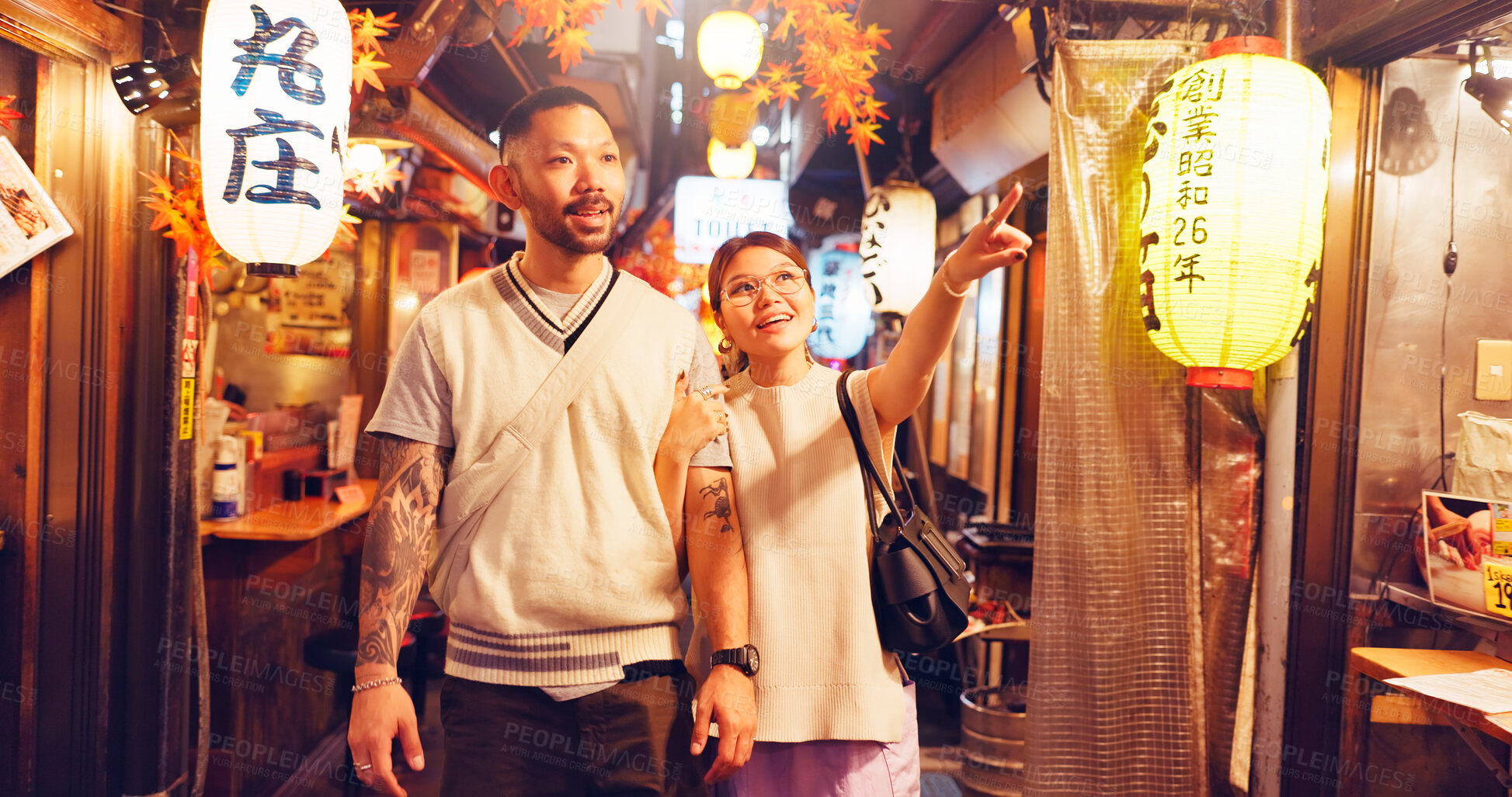 Buy stock photo Couple, night and walking at town market in Japan, love and bonding on honeymoon vacation. People, pointing and outdoor support on holiday in city, travel together and explore culture or sightseeing