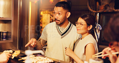 Buy stock photo Street food, night and shopping of Japanese couple at market for culture festive, nutrition or health. Travel, hunger and cuisine with man and woman at Japan city vendor for date and holiday