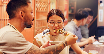 Buy stock photo Man, feeding and woman in restaurant for Asian food in city for romantic dinner, meal or anniversary. Couple, eating and bonding together with holiday, vacation and help for tourism or night in Japan