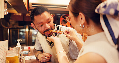 Buy stock photo Woman, feeding and man for romantic dinner, meal or anniversary in restaurant for Asian food in city. Couple, eating and bonding together with holiday, vacation and help for tourism or night in Japan