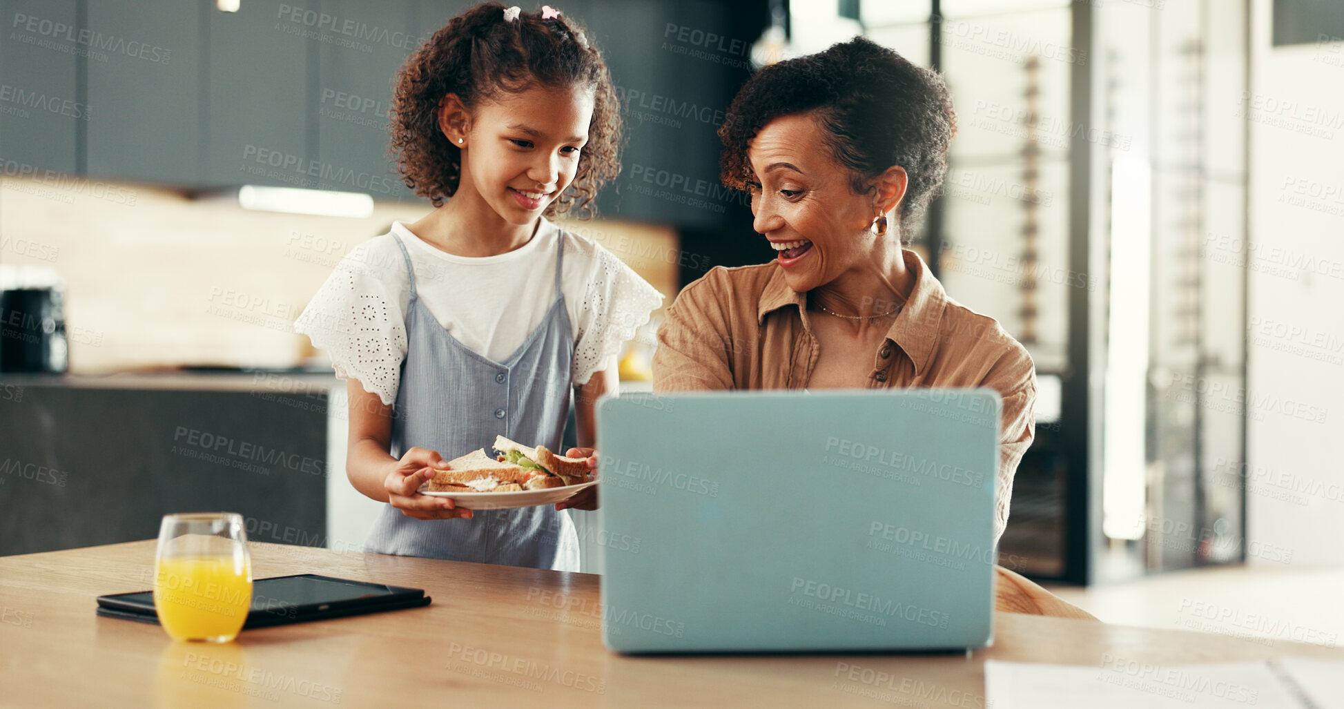 Buy stock photo Happy, lunch and child with mom on laptop in kitchen with food for nutrition, eating and wellness. Family, remote worker and girl with sandwich for mom for bonding, love and care on break in home