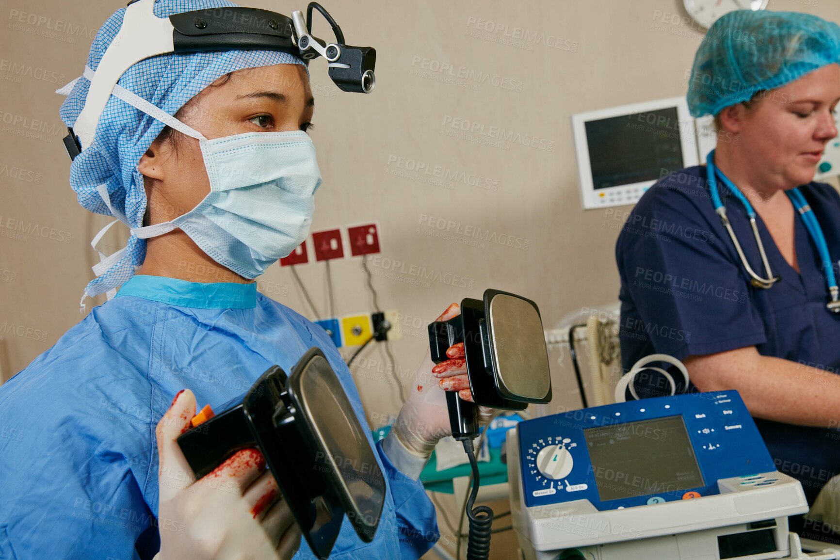 Buy stock photo Shot of a surgeon using a defibrillator on a patient during surgery