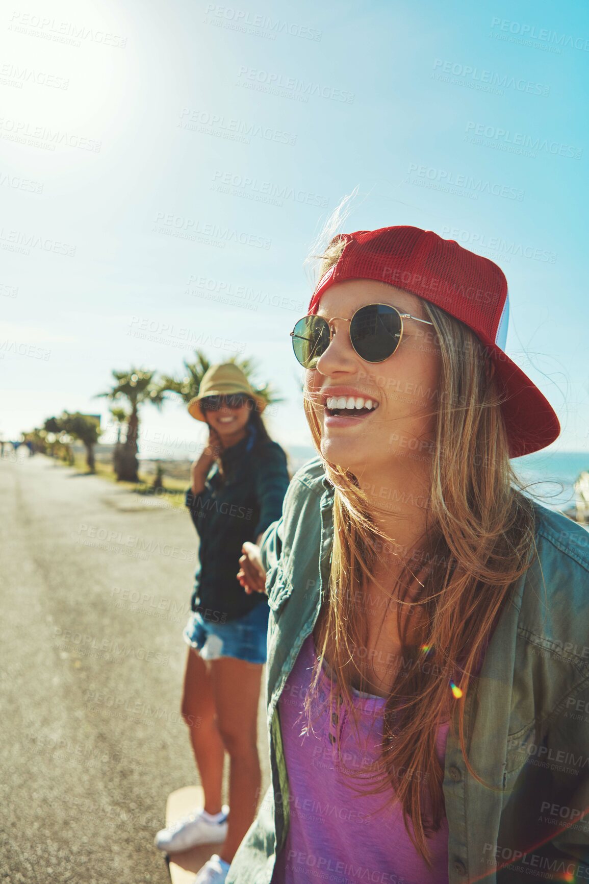 Buy stock photo Shot of two friends hanging out on the boardwalk with a skateboard