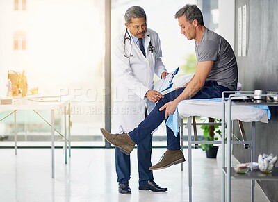 Buy stock photo Shot of a mature doctor examining his patient who is concerned about his knee