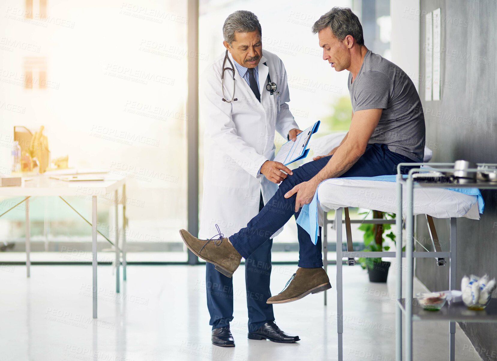 Buy stock photo Shot of a mature doctor examining his patient who is concerned about his knee