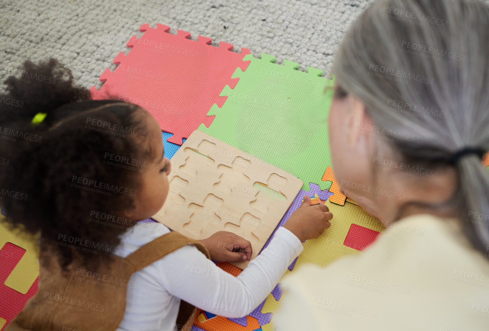 Buy stock photo Teacher, therapist and girl child with puzzle for education, assisted learning or childhood development. Woman psychologist, above or kid with jigsaw toys for support, playing or adhd therapy in home