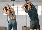 Active, sporty fitness couple or gym partners and friends training together, standing and doing arm stretching exercises. Back view of male trainer and female athlete warm up before workout class.