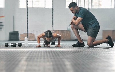 Buy stock photo Fit and athletic woman training with her personal trainer at the gym. An active female athlete doing pushups with her coach for her morning workout routine at a fitness and exercise facility