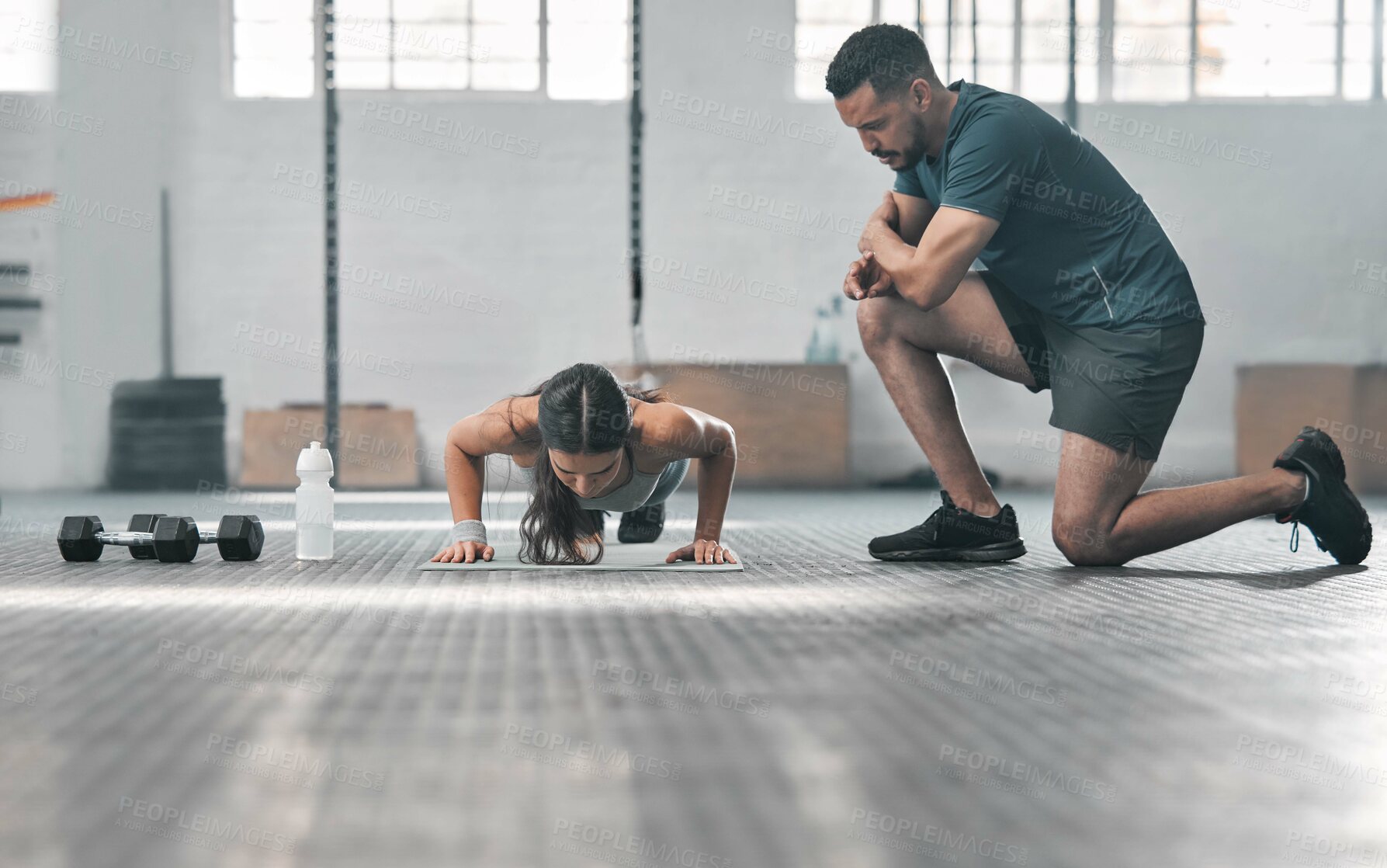 Buy stock photo Fit and athletic woman training with her personal trainer at the gym. An active female athlete doing pushups with her coach for her morning workout routine at a fitness and exercise facility