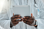 Doctor holding and using a digital tablet while working at a hospital alone. Expert medical professional doing research on a digital tablet while at work at a clinic