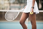 Closeup on the hands of a tennis player on the court. African american tennis player holding her ball and tennis racket on the court. Woman ready to compete in a tennis match at her club