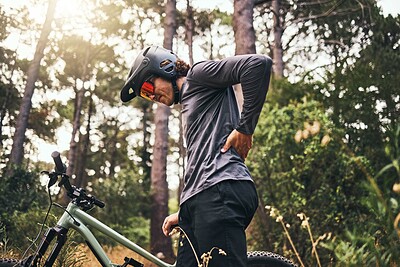 Buy stock photo Bicycle, back pain injury and man in forest cycling for fitness, outdoor travel or sports wellness with nature lens flare. Marathon sport person training in mountain bike or motorcycle muscle injury