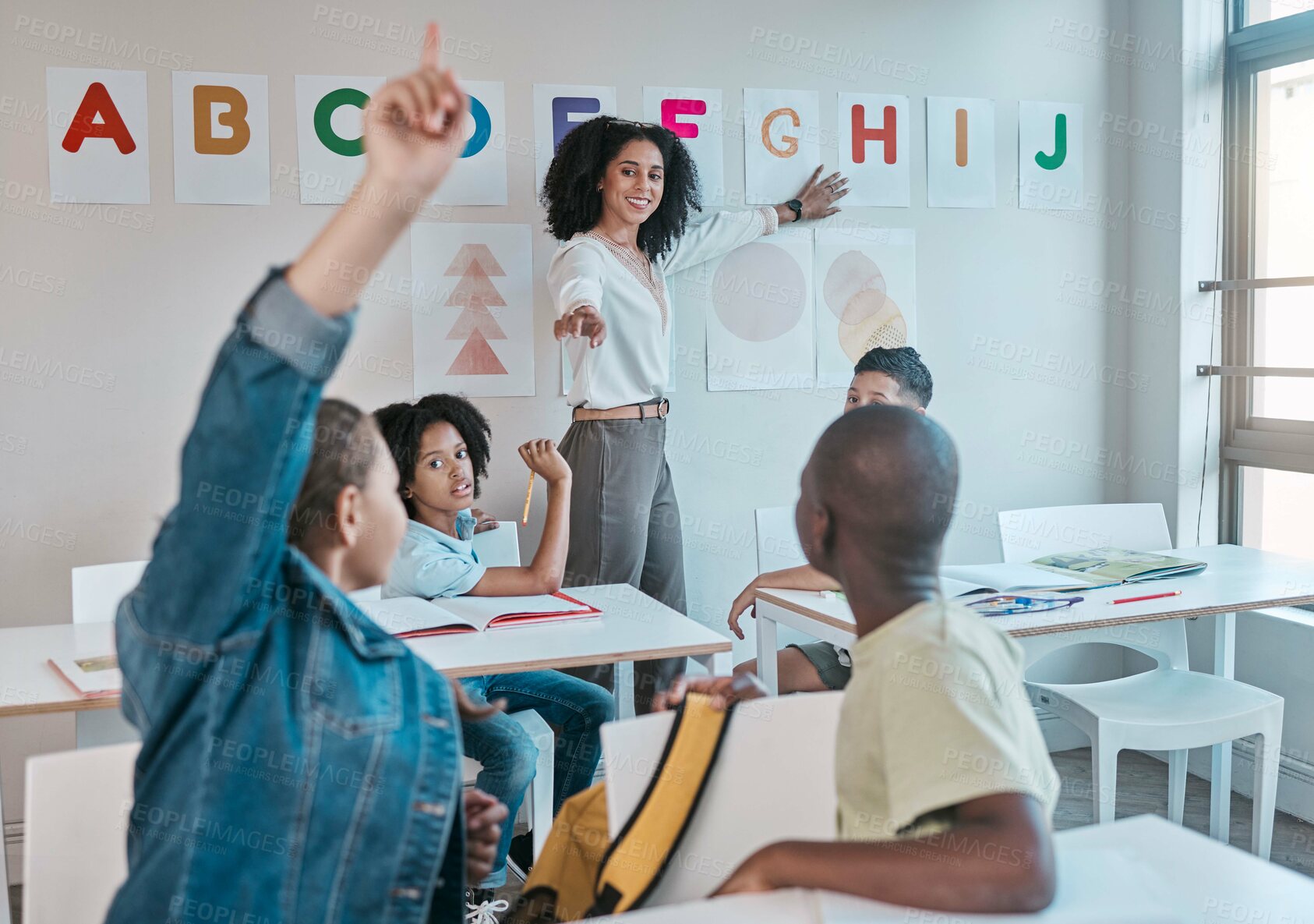 Buy stock photo Teacher, classroom and education at school with children learning the alphabet and answer a question. Raised hands, learners and tutor teaching for child development in a class with smart kids