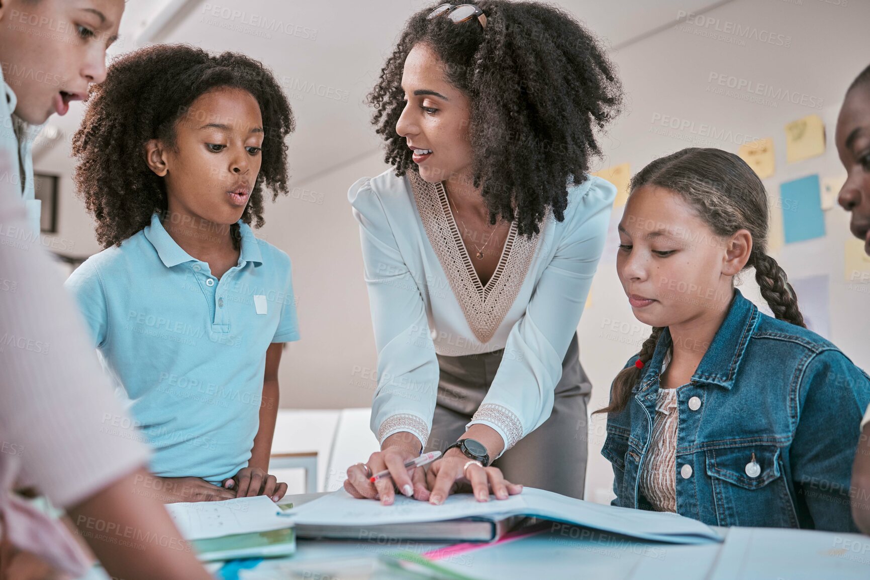 Buy stock photo Female teacher asking student a question, children learning in classroom and sign homework in book. School for teaching, educator reading kids notebook and group working together for assessment