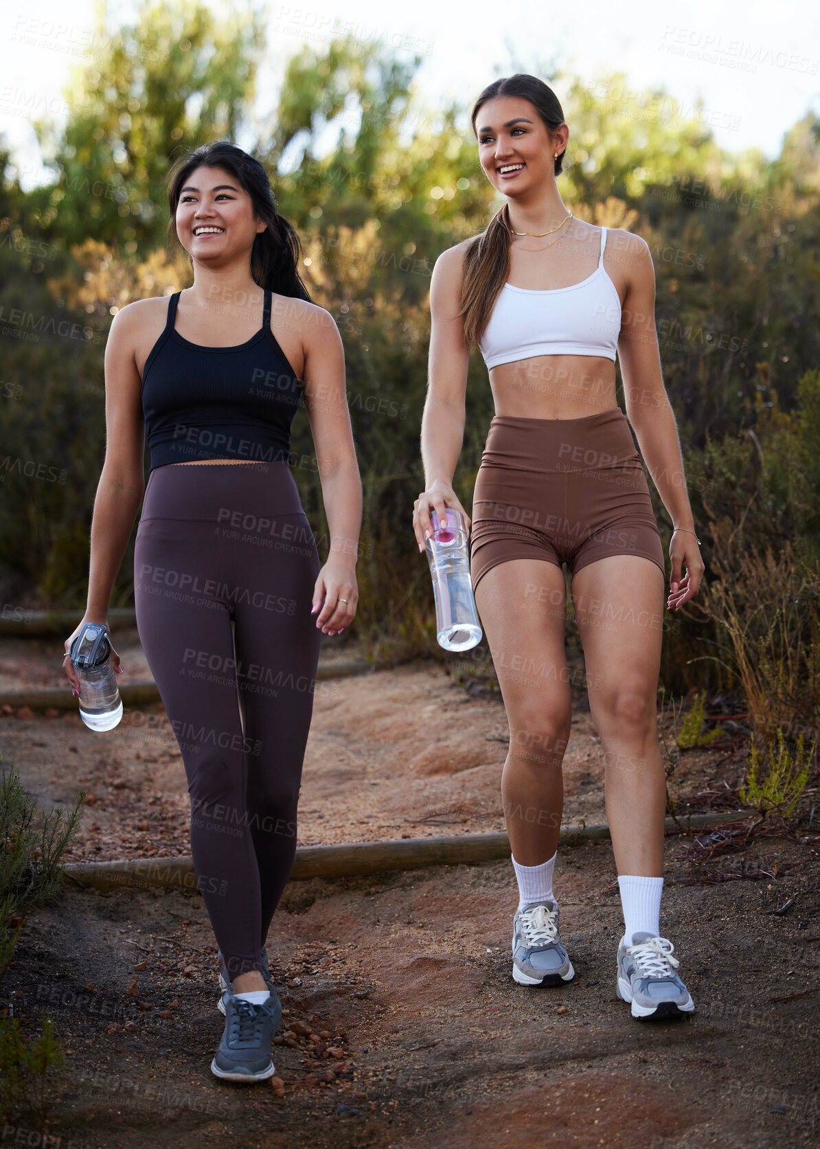 Buy stock photo Fitness women or friends walking in nature with water bottle for workout, running and cardio training together. Diversity athlete, sports or runner people in woods with diet, body and wellness goals