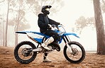 Motorcycle, person and sports in woods with training for competition, ride in nature with action and helmet. Extreme, adrenaline and exercise, athlete and transport with dirt bike, freedom and travel