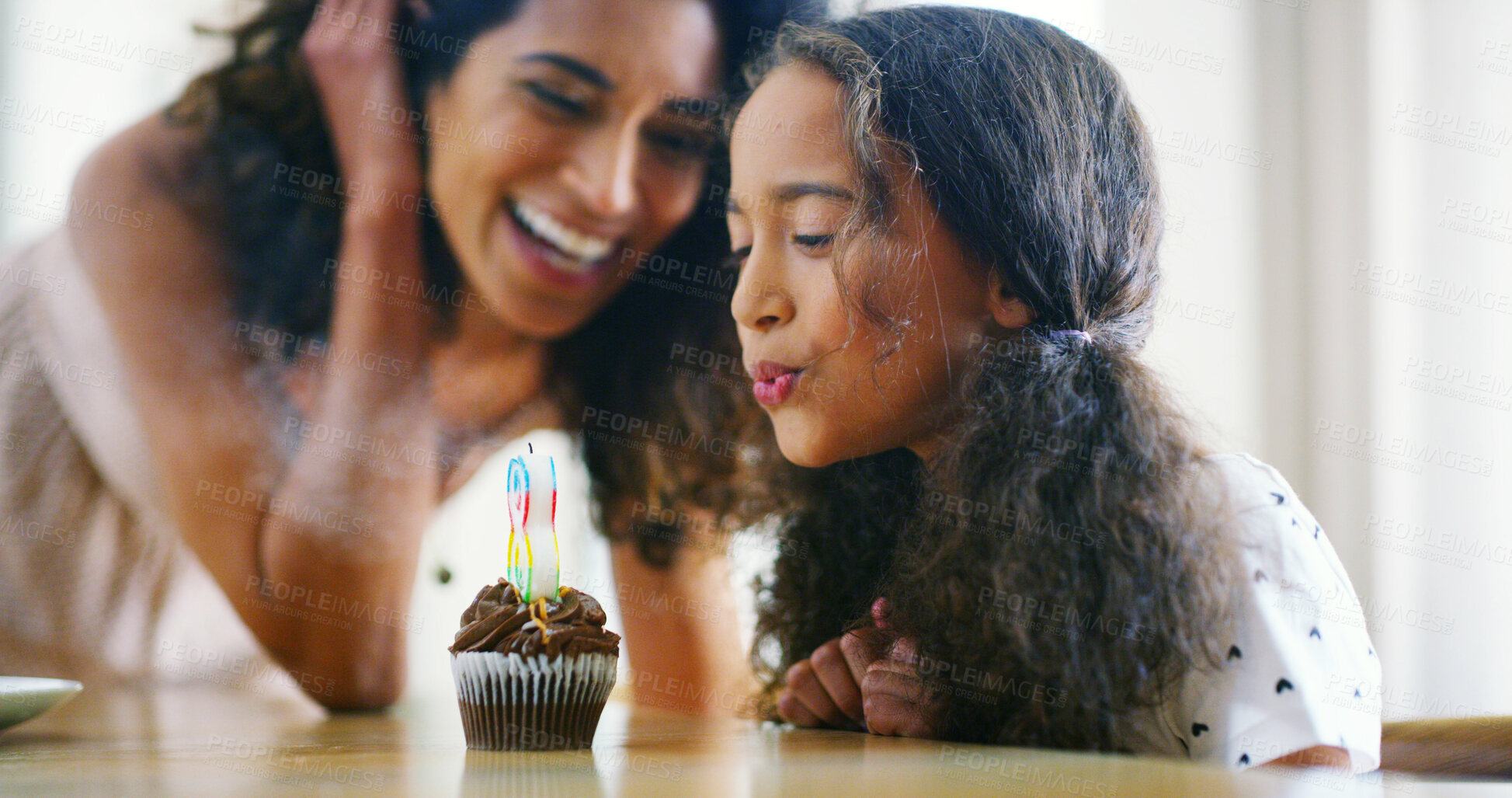 Buy stock photo Mother, girl and blowing candle on cupcake for birthday celebration, support and care at home. People, parent and happy with kid as family for memories, dessert and special occasion with bonding