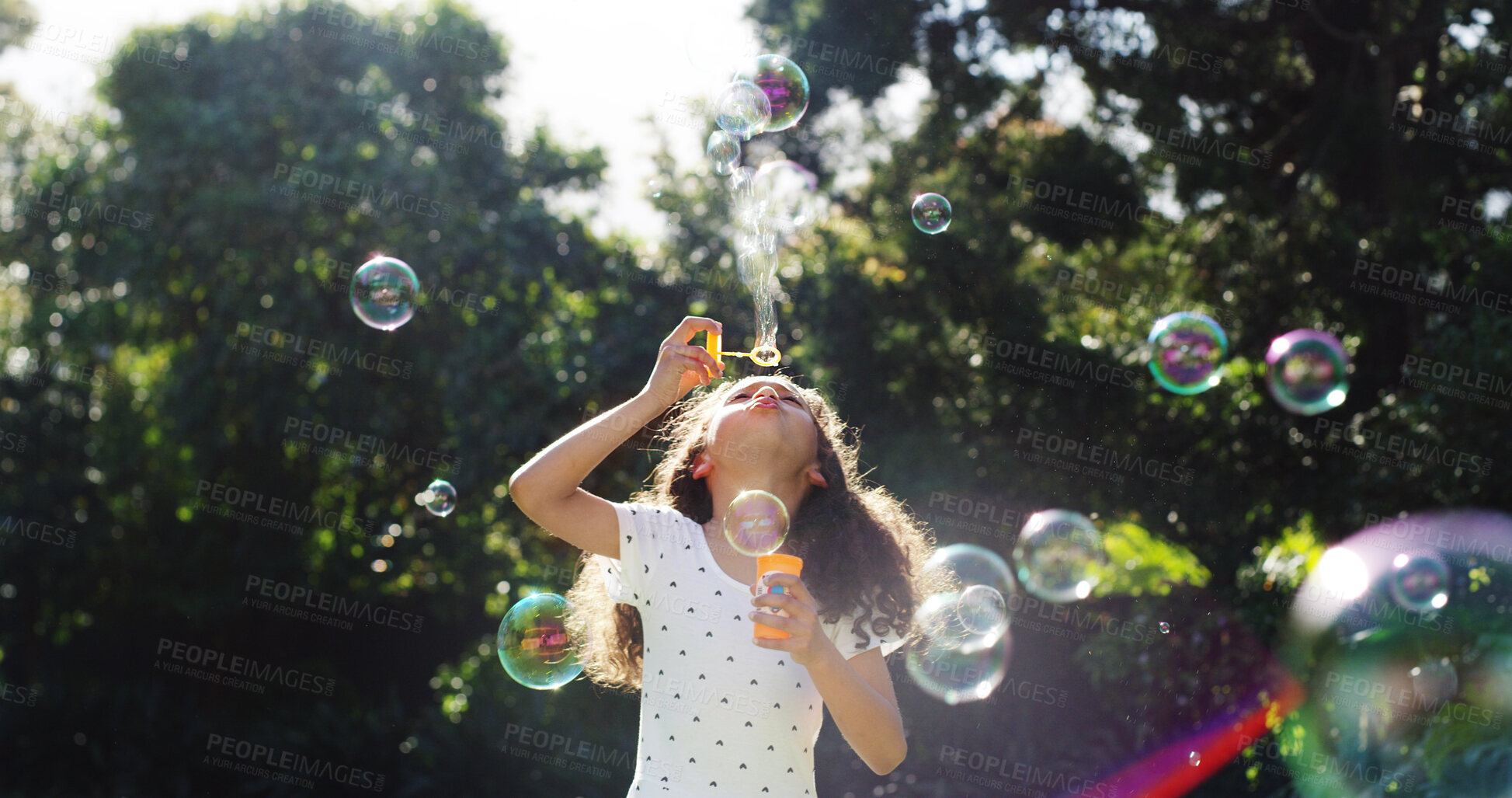 Buy stock photo Kid, blowing and bubbles in air outdoor for playful fun, learning activity and sensory stimulation. Child, girl and wand with soap for games, fine motor skills and creative imagination in backyard