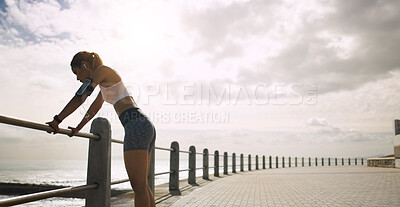 Buy stock photo Seaside, woman and retired from running with fitness on earphones for wellness, health and self care. Female person, cloudy sky and space on break with jogging as workout, training and exercise