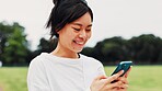 Asian, happy woman and typing with phone in nature for communication, chat or online app at park. Japan, female person or user on mobile smartphone for texting, message or browsing network for sport