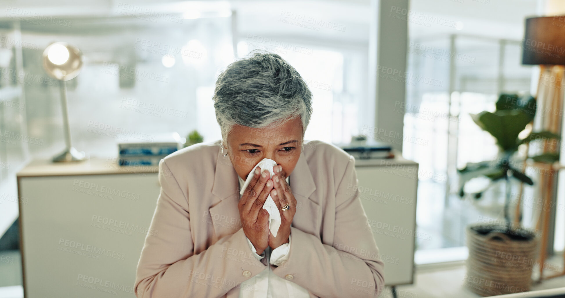 Buy stock photo Sick, mature woman and blowing nose with tissue for viral infection, hayfever or allergies at office desk. Senior, female person or employee with virus, cold or flu for influenza, cough or sneeze