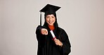 Pointing, graduation and diploma with portrait of asian woman in studio for success, college degree or pov. Achievement, education and university student with person on white background for mockup