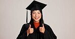 Thumbs up, graduation and smile with portrait of asian woman in studio for success, college degree or award. Achievement, education and university student with person on white background for mockup