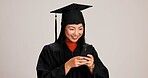 Woman, studio background and smile for graduation on smartphone with text message for congratulations. Asian person, university student and happy or excited for social media, communication and chat