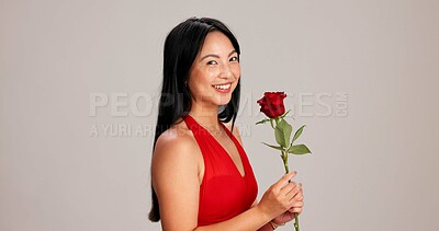 Buy stock photo Woman, studio background and happy with rose on portrait for love, care and valentines day celebration in Japan. Japanese person, romance and smile in red dress with flower as anniversary gift 