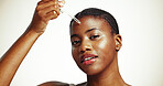 Portrait, skincare and black woman with serum for glow, detox treatment or beauty on white studio background. Face, dropper and model apply cosmetics with essential oil, hyaluronic acid and vitamin c