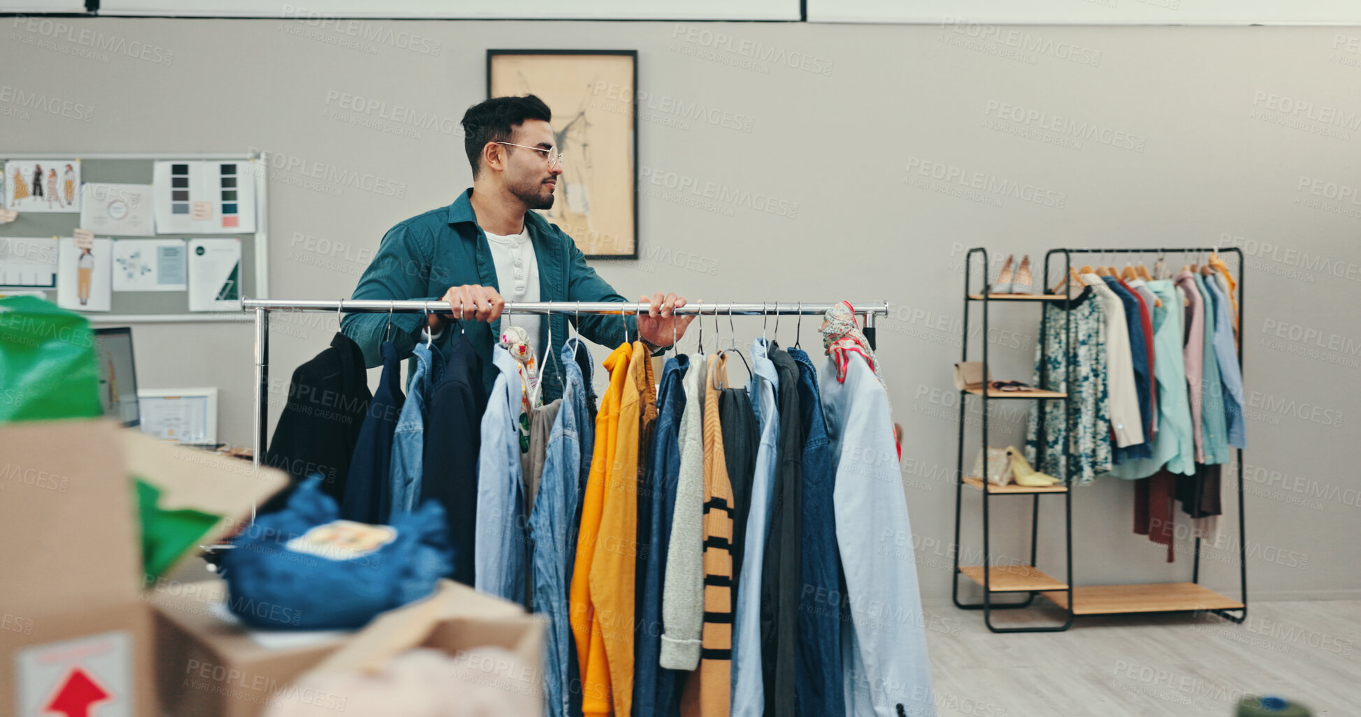 Buy stock photo Clothing rack, creative and outfit with fashion designer man in textile workshop for preparation. Choice, decision and options with style director in office for clothes production or manufacturing