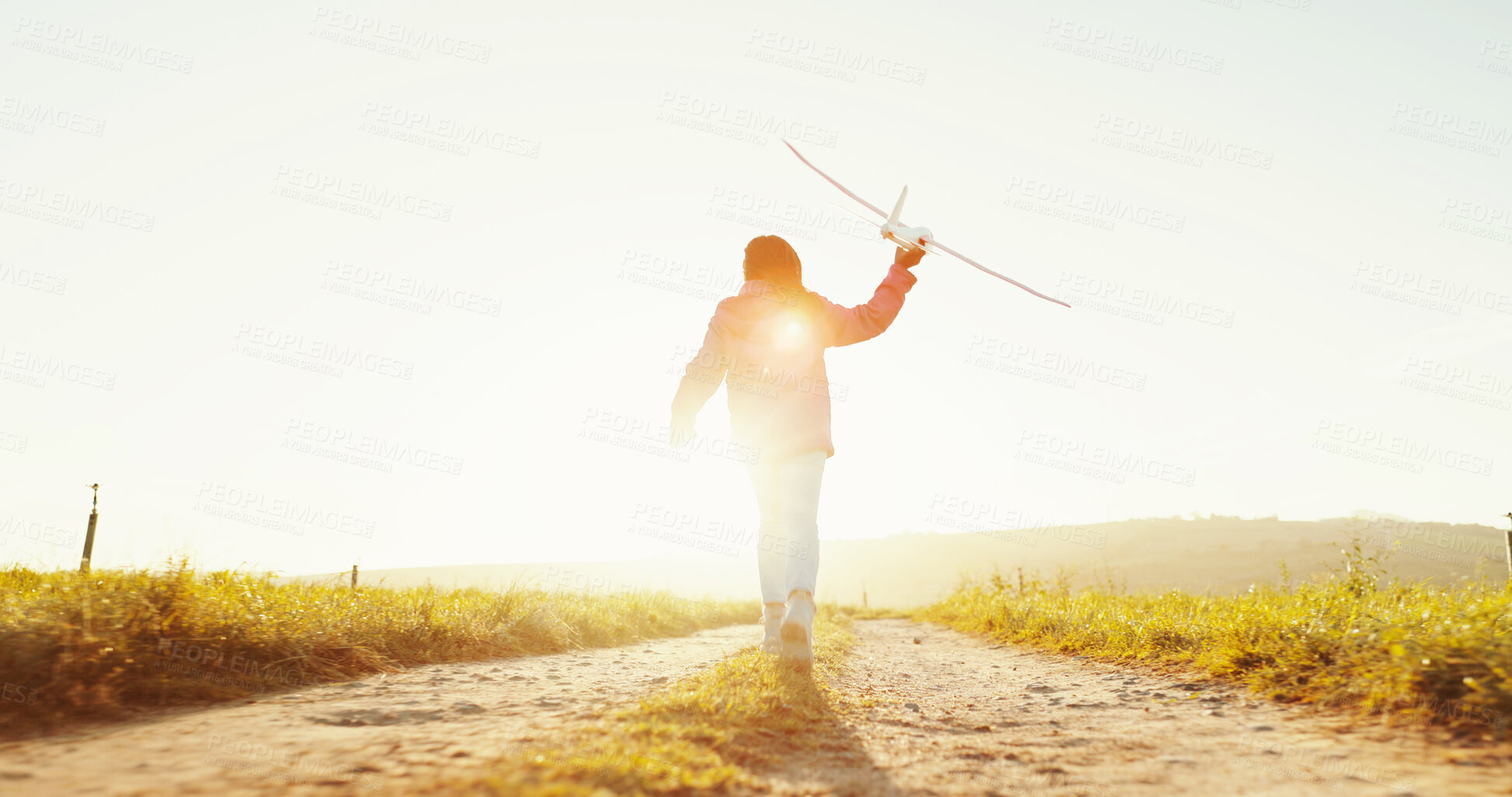 Buy stock photo Child, outdoor and play with airplane at sunrise for game, freedom or travel on mockup space. Back, girl or kid running with plane in sky for flight, toy or vacation on countryside path for adventure