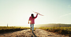 Child, running outdoor and play with airplane for game, freedom and travel on mockup space. Back, girl and kid with toy plane by sky for flight, vacation and sunset on countryside path for adventure