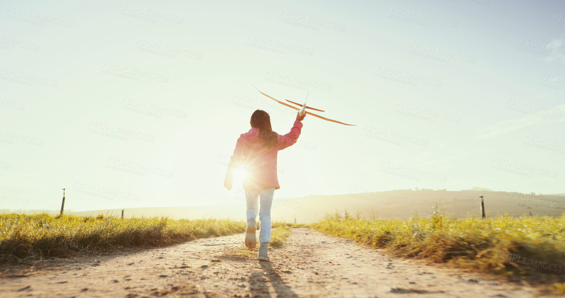 Buy stock photo Kid, running outdoor and play with airplane for game, freedom and travel on mockup space. Back, girl and child with toy plane by sky for flight, vacation and sunrise on countryside path for adventure