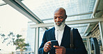 Cellphone, walking and businessman in city with communication for corporate travel with email. Network, commuting and African mature CEO with online hotel checkin with phone for company trip in town.