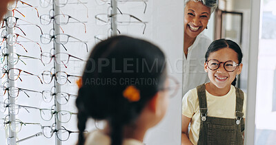 Buy stock photo Child, optometrist and choosing frame in mirror, prescription glasses and helping client. Woman, optical store and specialist consulting at clinic for girl, excited kid and lens shopping at eye exam